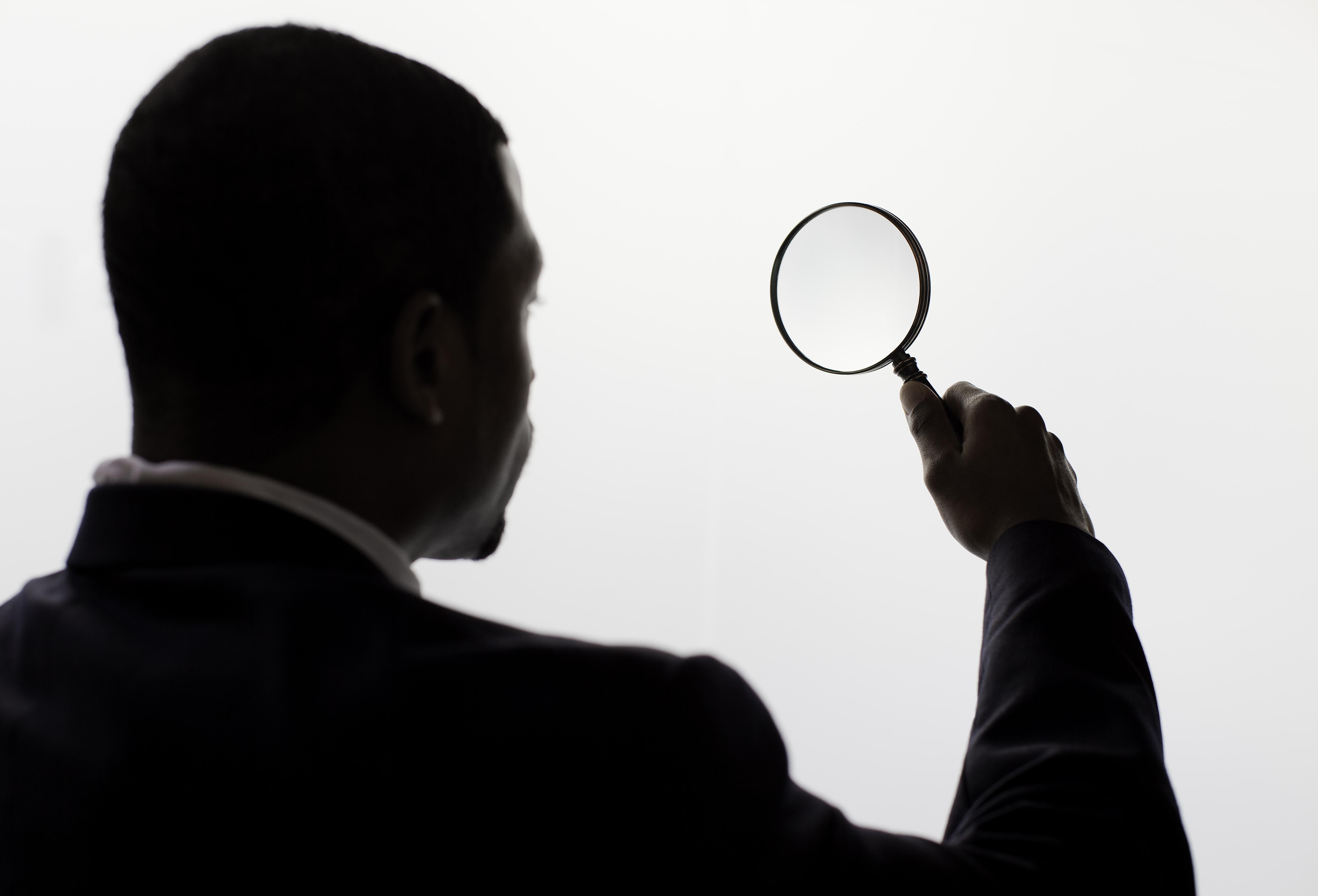 A man looking through a magnifiing glass.